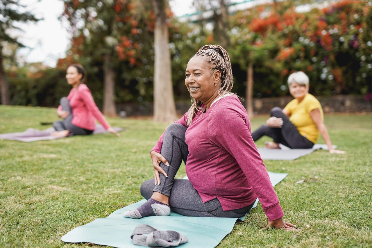 A woman stretching in the park after a kyphoplasty and vertebroplasty procedure.