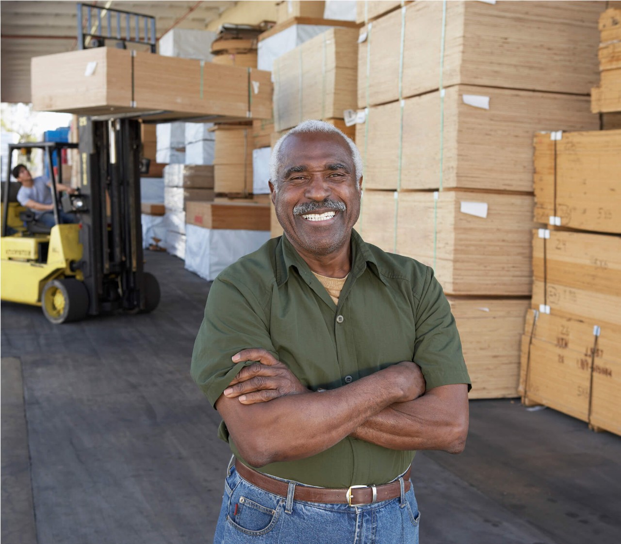 A man surrounded by stacks of lumber happy about his prostate artery embolization procedure